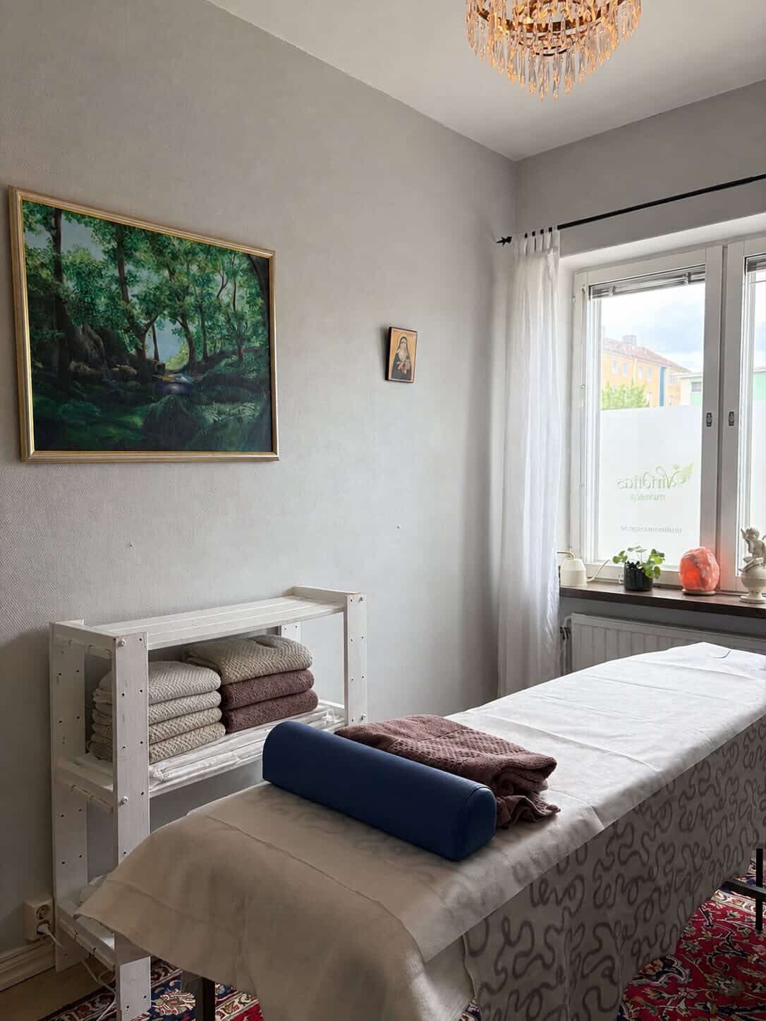 Behandlingsrum hos Viriditas i Uddevalla med massagebänk, mjuka handdukar och tavla av grön skog
